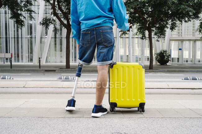 Disabled man with luggage standing at railroad station — Stock Photo