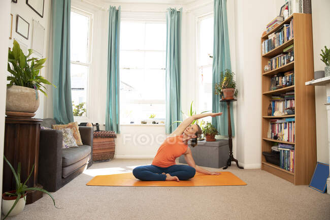 Donna matura che fa braccio sollevato esercizio di stretching a casa — Foto stock