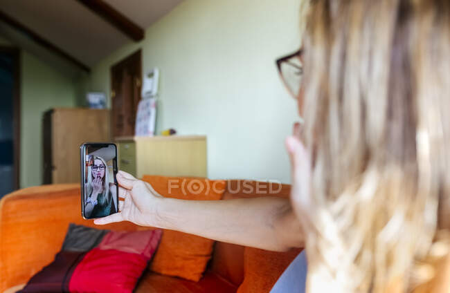 Mother and daughter blowing kisses to each other while on video call through mobile phone at home — Stock Photo