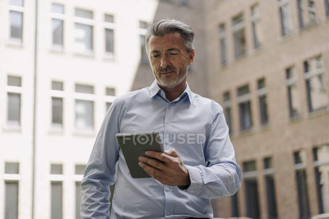 Empresario usando tableta digital mientras está parado contra la construcción - foto de stock