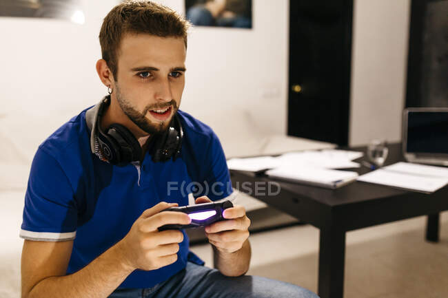 Hombre guapo disfrutando mientras juega videojuego en casa - foto de stock