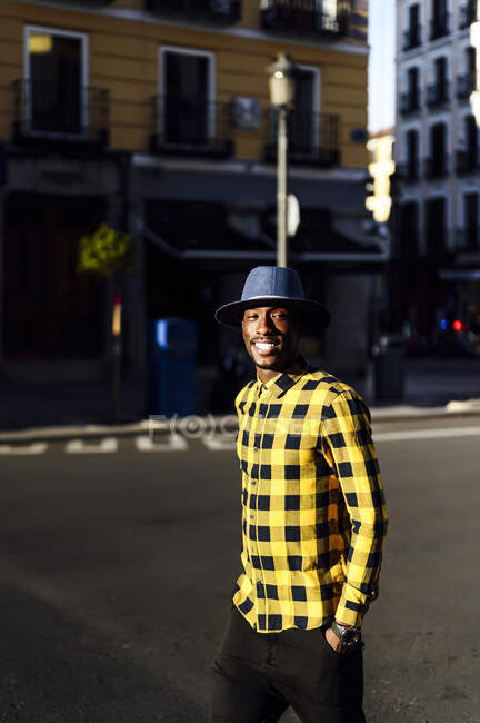 Впевнений африканський чоловік з руками в кишенях у капелюсі в місті — стокове фото