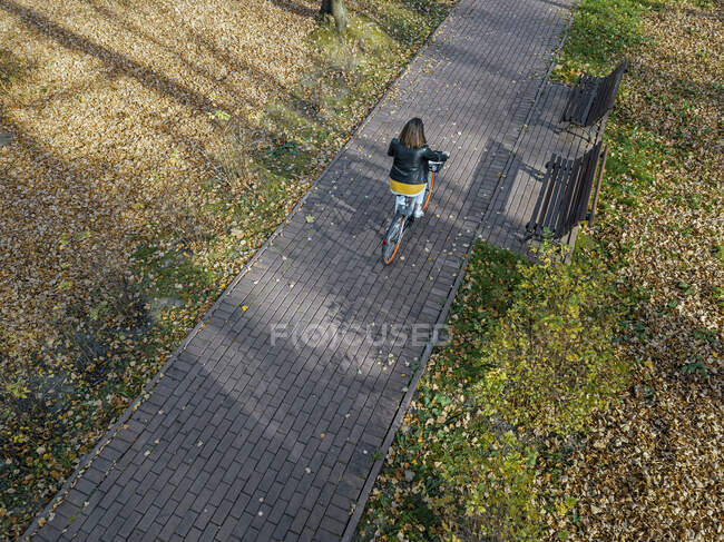 Femme à vélo dans le parc public pendant l'automne — Photo de stock
