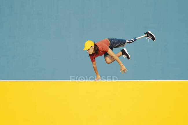 Homme handicapé physique sautant contre un mur multicolore — Photo de stock