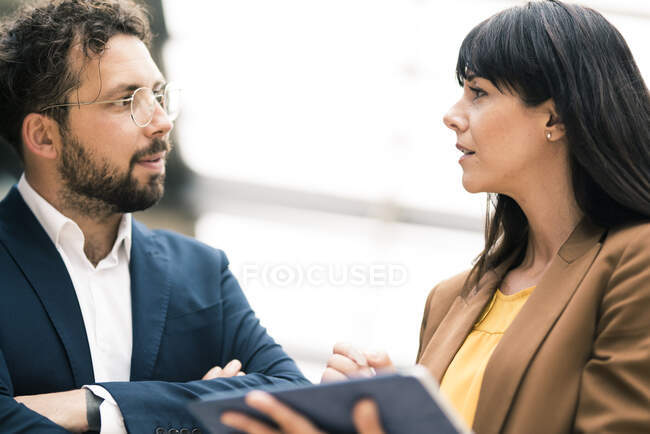 Businesswoman with digital tablet discussing with male colleague at office — Stock Photo