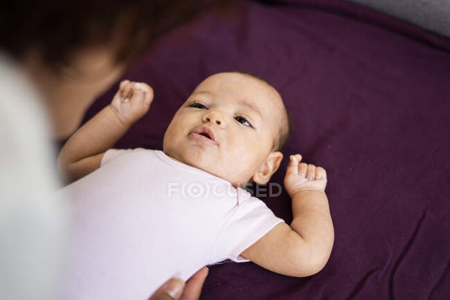 Mujer jugando con el bebé acostado en el sofá en casa - foto de stock