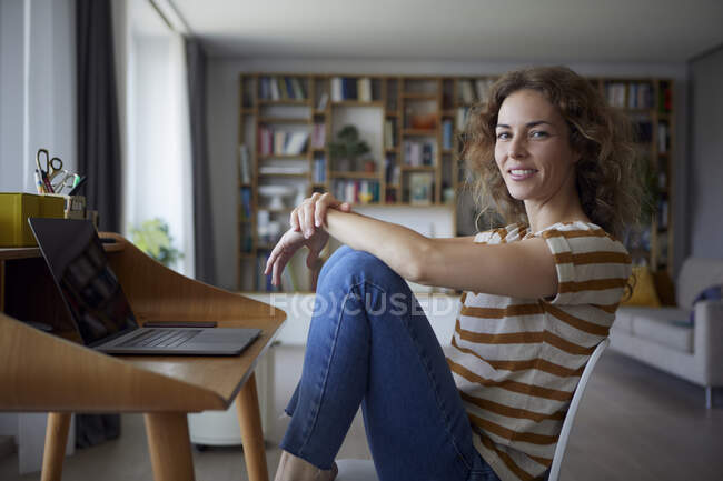 Femme souriante assise sur une chaise à la maison — Photo de stock