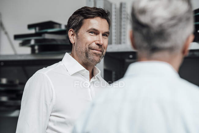 Smiling colleague discussing with manager while standing in manufacturing factory — Stock Photo