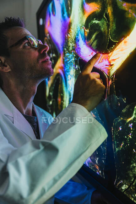 Male scientist pointing at projection of human brain with nerve fiber examining at laboratory — Stock Photo