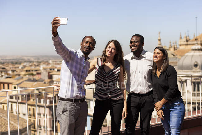 Happy multi-ethnic colleagues taking selfie at office rooftop during break — Stock Photo