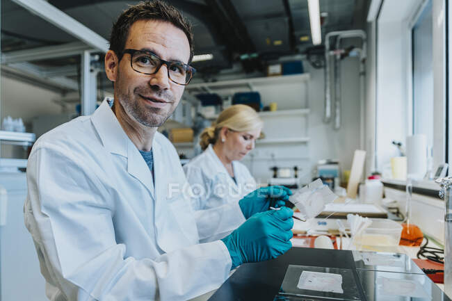 Wissenschaftler hält menschliches Gehirnmikroskop-Dia, während er neben Labormitarbeiter sitzt — Stockfoto