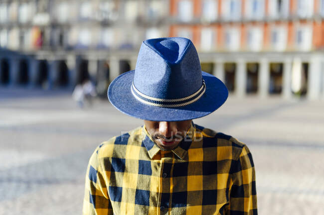 Hombre africano usando sombrero mientras está de pie en la ciudad - foto de stock