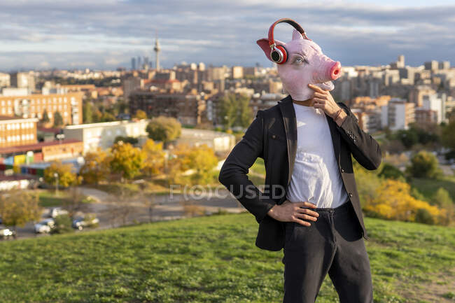 Духовний чоловік, який носить маску свині і бездротові навушники проти неба. — стокове фото