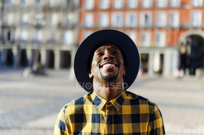 Lächelnder afrikanischer Mann mit Hut schaut in der Stadt auf — Stockfoto