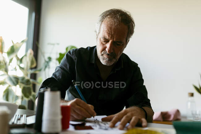 Male costume designer making sketch on paper at work studio — Stock Photo