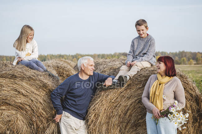 Nonni con nipoti seduti su balle di fieno — Foto stock