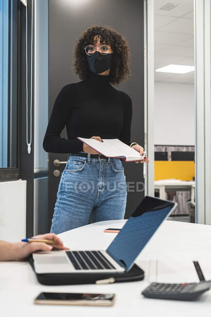 Businesswoman with diary looking away while colleague using laptop at desk in office — Stock Photo
