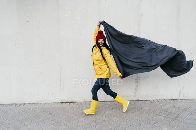 Жінка в плащі тримає ковдру, ходячи по стіні по стежці. — стокове фото