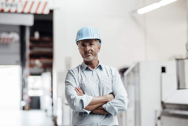 Confident male engineer standing with arms crossed in industry — Stock Photo