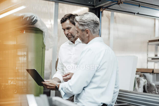 Чоловіки-інженери обговорюють через ноутбук, стоячи в промисловості. — стокове фото