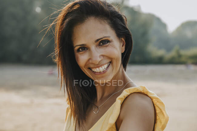 Femme souriante debout à la plage par une journée ensoleillée — Photo de stock