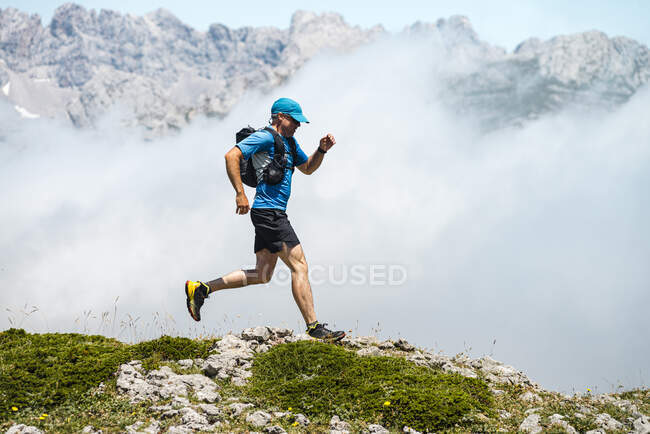 Mature sportsman trail running through foggy mountains — Stock Photo