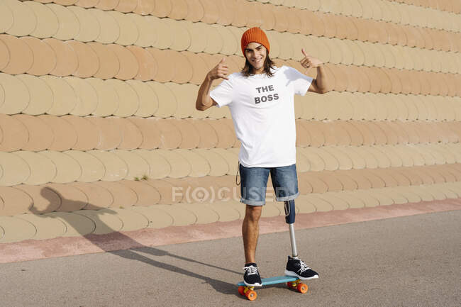 Jeune homme handicapé debout sur le skateboard au terrain de sport — Photo de stock