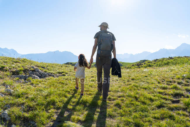 Father and daughter walking on grass during summer — Stock Photo