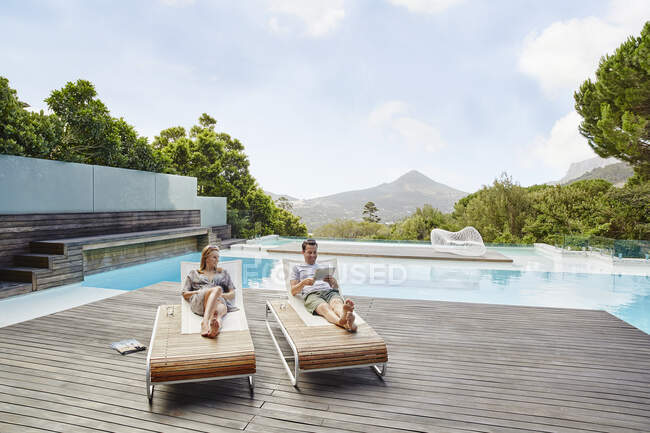 Heterosexuelles Paar legt sich auf Deck gegen Swimmingpool — Stockfoto