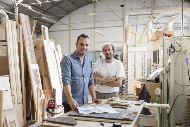 Smiling project manager standing by coworker in factory — Stock Photo