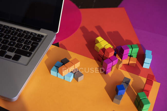 Ordenador portátil y bloques de colores en la mesa en casa - foto de stock