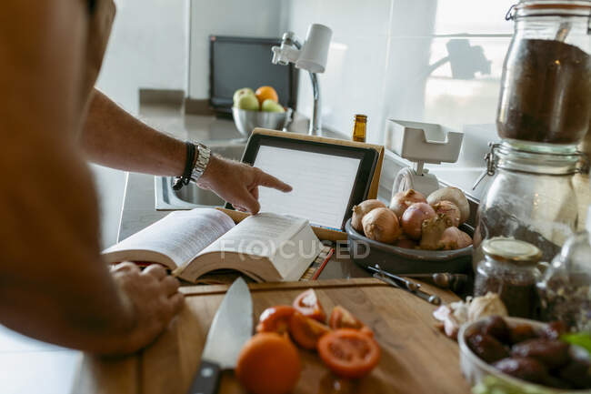 Обрезанное изображение человеческой руки с помощью цифрового планшета на кухне — стоковое фото