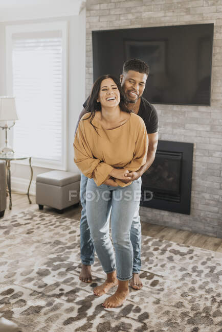 Homme embrassant la femme par derrière tout en se tenant à la maison — Photo de stock
