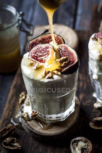 Glass of Greek yogurt with honey, figs and walnuts — Stock Photo