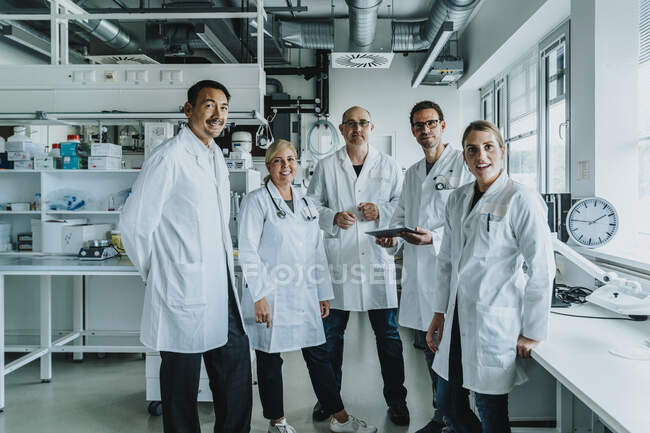 Squadra di scienziati fiduciosi in piedi insieme in laboratorio — Foto stock