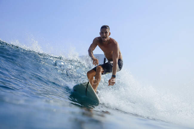 Homem sem camisa despreocupado surfando na onda do mar contra o céu limpo — Fotografia de Stock