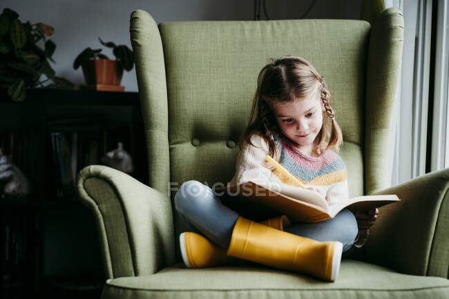 Ragazza che fa i compiti mentre seduto sulla sedia a casa — Foto stock