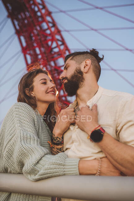Пара, стоячи на мосту в місті під час заходу сонця — стокове фото