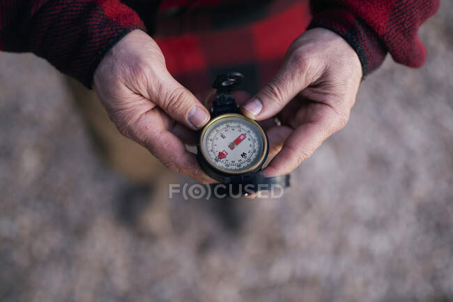 Cropped image of bushcrafter holding navigational compass while hiking — Stock Photo