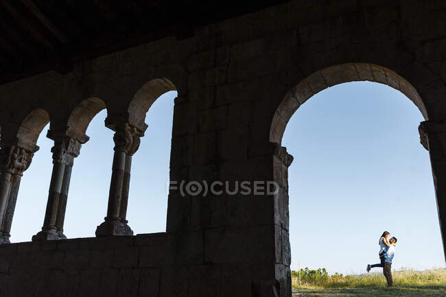 Молодий чоловік піднімає дівчину крізь арку римської церкви. — стокове фото