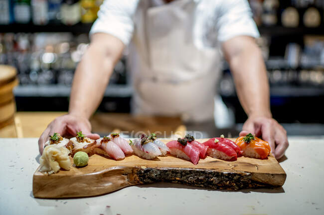 Chef maschile con sushi su vassoio di servizio in legno in cucina al ristorante — Foto stock