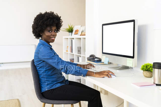 Jeune femme travaillant sur ordinateur tout en étant assis à la maison — Photo de stock
