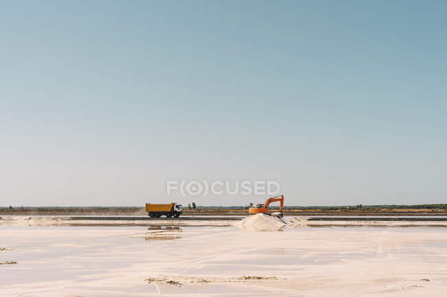 Spanien, Provinz Huelva, Huelva, Klarer Himmel über LKW und Erdbewegungsmaschinen, die in der Salzebene arbeiten — Stockfoto