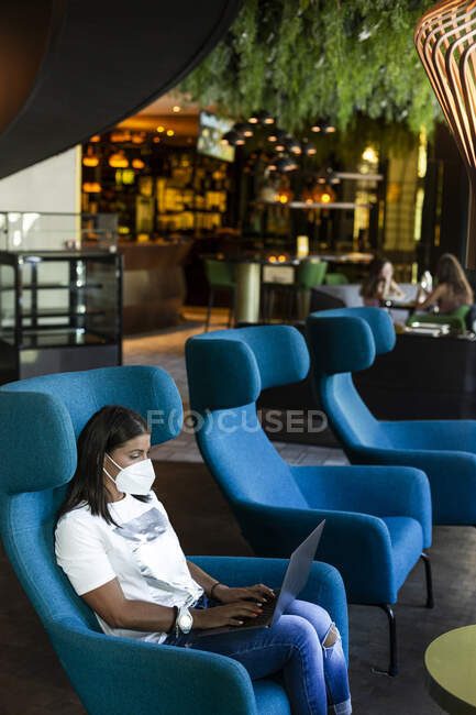 Businesswoman using laptop while sitting on chair in modern bar — Stock Photo