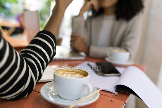 Compañeras de trabajo con bebida de café en la mesa en el café - foto de stock