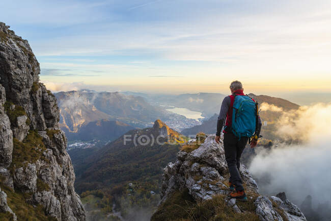 Pensoso escursionista di sesso maschile che cammina sulla vetta della montagna durante l'alba alle Alpi Bergamasche, Italia — Foto stock
