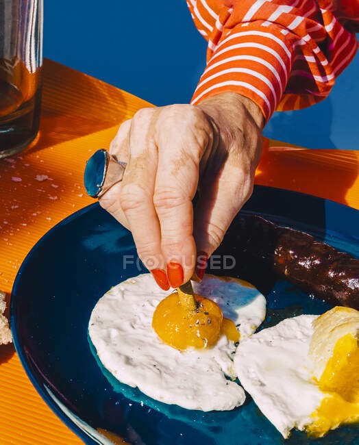 Hand of senior woman extinguishing cigarette in fried egg — Stock Photo