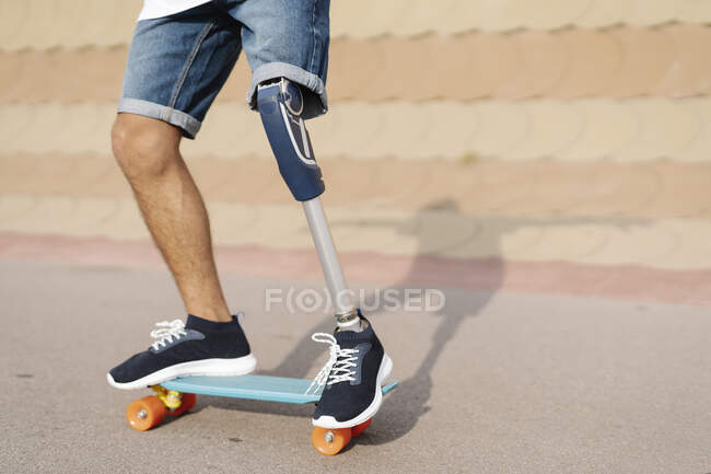 Athlète avec membre artificiel et pied debout sur planche à roulettes à la cour — Photo de stock