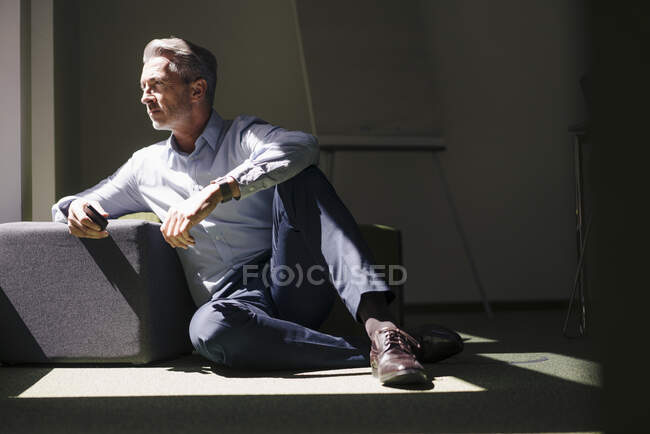 Бізнесмен сидить біля хаска на підлозі при офісі. — стокове фото
