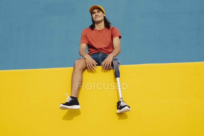 Athlète souriant assis sur un mur multicolore — Photo de stock